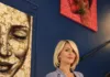 ViArt 2nd Floor inaugura la stagione 2026/2027 con la mostra collettiva PluraMens Una donna con giacca chiara è in piedi in una sala con opere d’arte alle pareti.