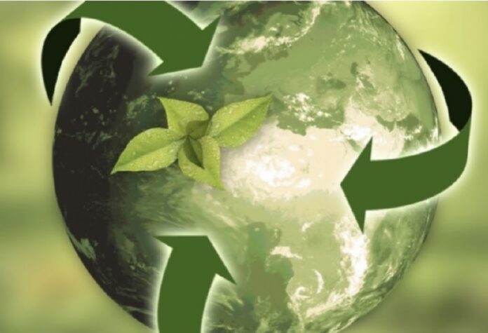 Terra verde con frecce di riciclo e foglie, simbolo di sostenibilità e protezione ambientale.