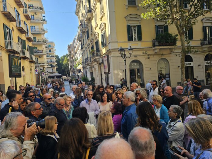 Persone radunate in una via di Napoli durante il Tour del Giallo, evento dedicato ai delitti e segreti tra le vie della città.