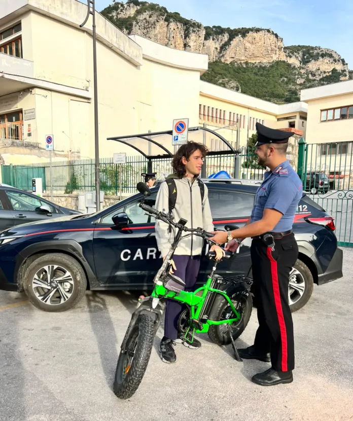 Foto di archivio di un carabiniere che parla con un ragazzo con bicicletta in un parcheggio