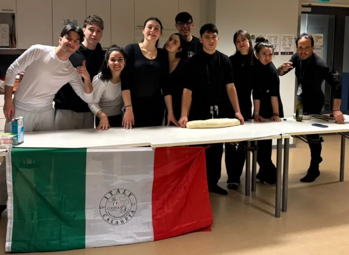 Un gruppo di persone in una sala, dietro un tavolo coperto in parte da una bandiera italiana.