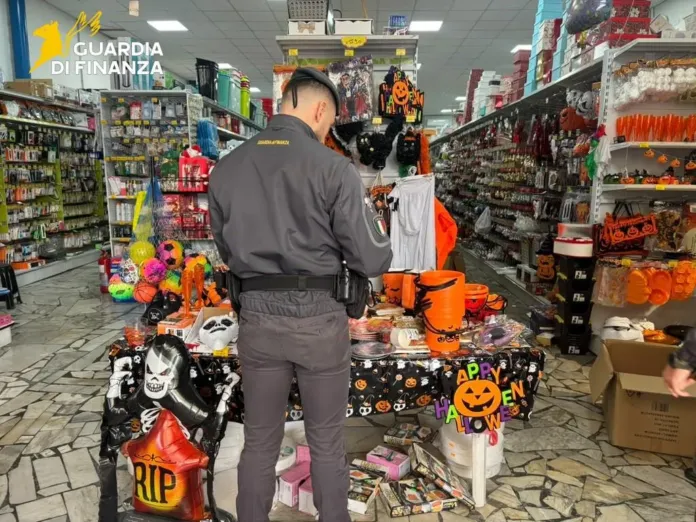 Un agente in divisa osserva prodotti e decorazioni di Halloween esposti tra gli scaffali e su un banco di un negozio.