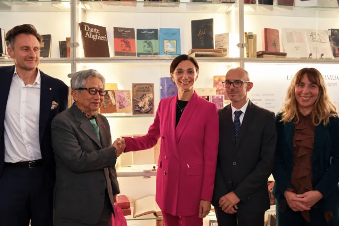 Persone davanti a scaffali con libri esposti; due di loro si stringono la mano.