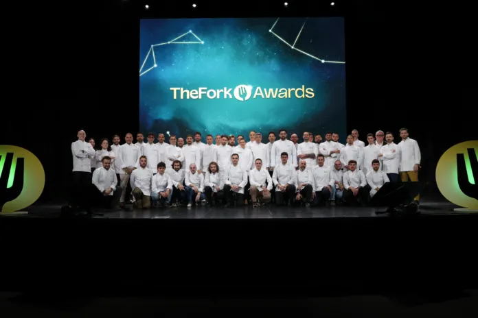 Un gruppo di persone in giacca da chef posa sul palco davanti a uno schermo con la scritta TheFork Awards.