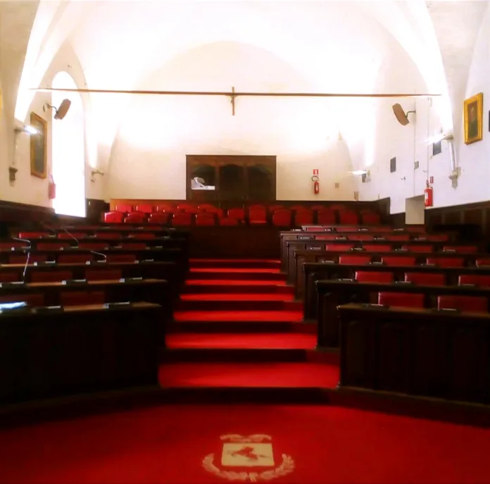 Fotografia di un'aula vuota con sedie rosse e scrivanie disposte in ordine, caricata come immagine di archivio.