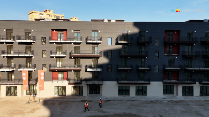 Palazzine di nuova costruzione a Scampia con balconi e cortile interno, sotto un cielo sereno.