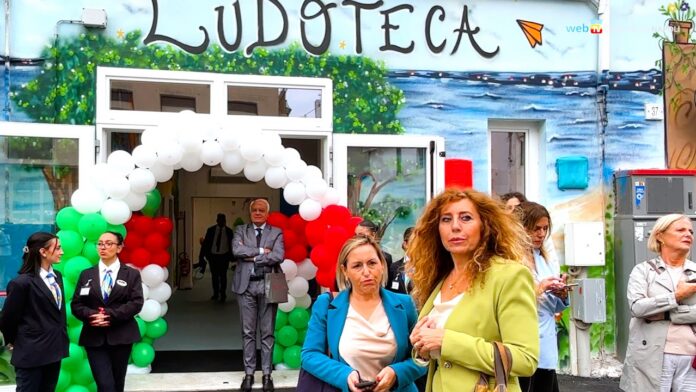 Ingresso colorato della ludoteca nel bene confiscato alla camorra con decorazioni e palloncini bianchi, verdi e rossi.