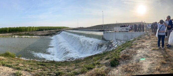 Vista panoramica dell'impianto idraulico con acqua che scorre e persone lungo la riva, immagine di archivio.