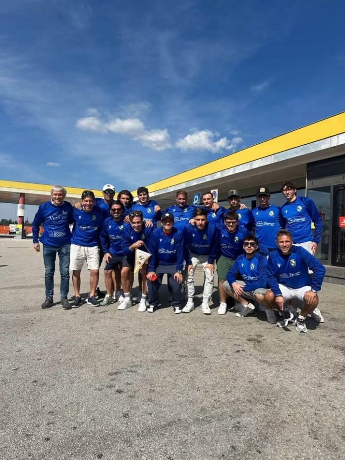 Squadra di calcetto di Tropea in posa, con magliette blu, all'aperto sotto il cielo soleggiato.