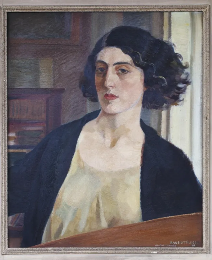 Dipinto a olio incorniciato raffigurante una donna con capelli scuri, giacca nera e abito chiaro, seduta davanti a una libreria.