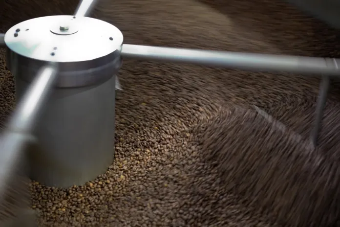 Chicchi di caffè si muovono in una macchina con componenti metallici.