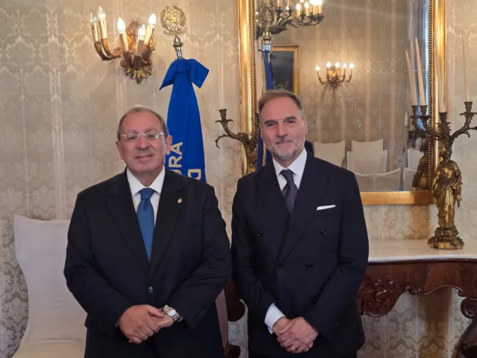 Incontro istituzionale tra due uomini in una sala formale con arredamento classico.