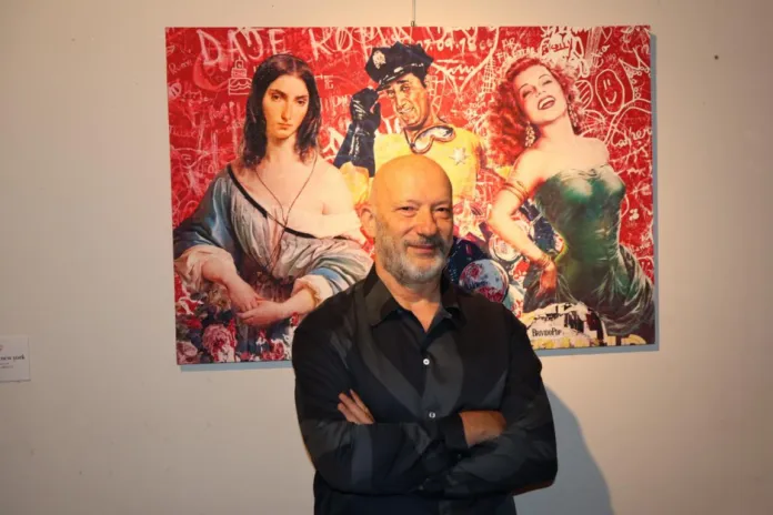 Artista davanti a una sua opera d'arte con sfondo rosso su parete in mostra personale a Roma