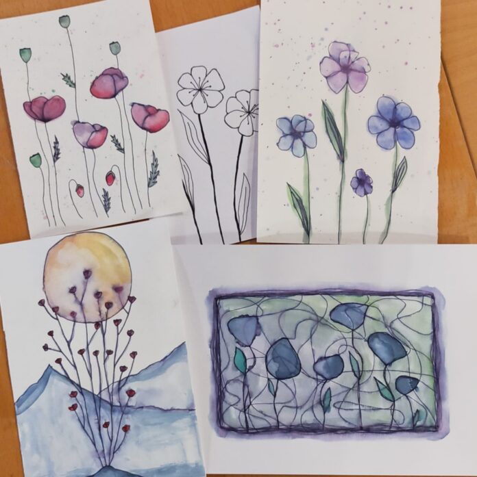 Disegni artistici di fiori creati con acquerelli e penna su fogli bianchi, rappresentano attività di laboratorio creativo per il benessere mentale.