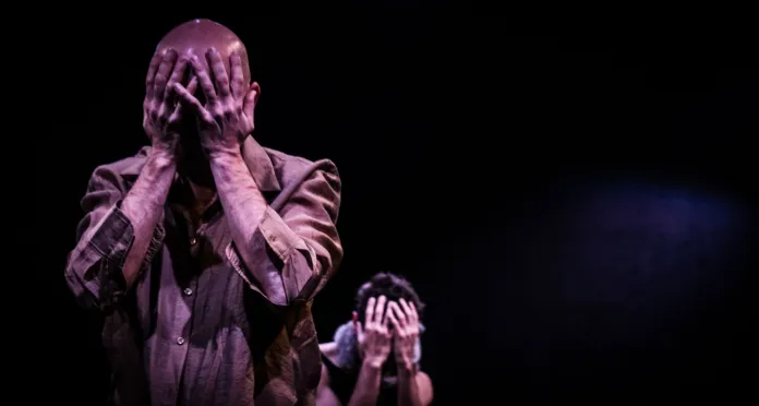 Immagine illustrativa di performance teatrale o di danza, scena drammatica con attore che copre il volto.