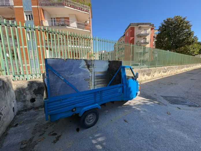 Motoveicolo blu parcheggiato su strada con cassone, simbolo del sequestro per trasporto illecito di rifiuti.