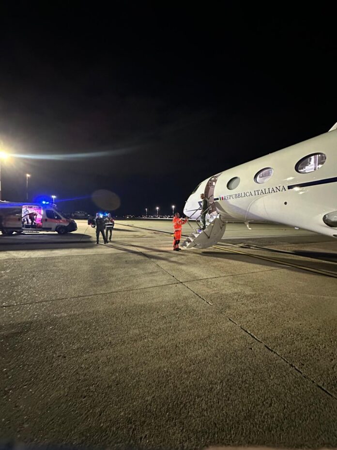 Aereo fermo sulla pista di notte, accanto a un mezzo di soccorso.