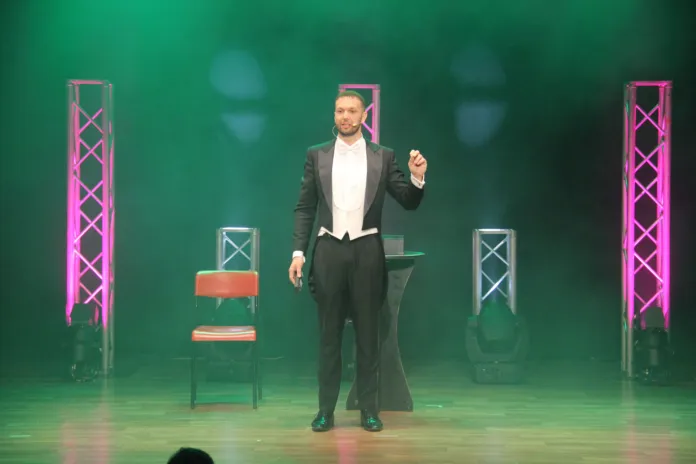 Fotografia di Francesco Frattarelli durante uno spettacolo teatrale, sul palco del Teatro Vittoria, con luci colorate sullo sfondo.