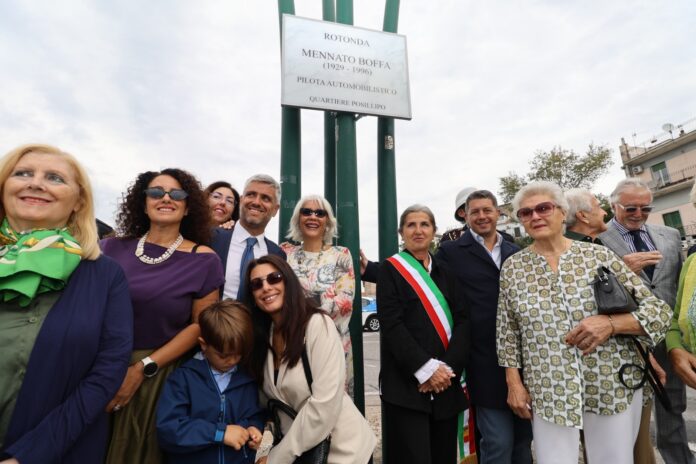Gruppo di persone in occasione dell'intitolazione della rotatoria a Mennato Boffa a Posillipo, con targa commemorativa visibile.