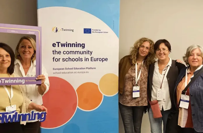 Persone in piedi accanto a un pannello con la scritta eTwinning.