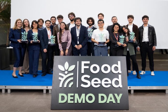 Un gruppo di persone posa su un palco davanti a un cartello con la scritta «FoodSeed Demo Day».