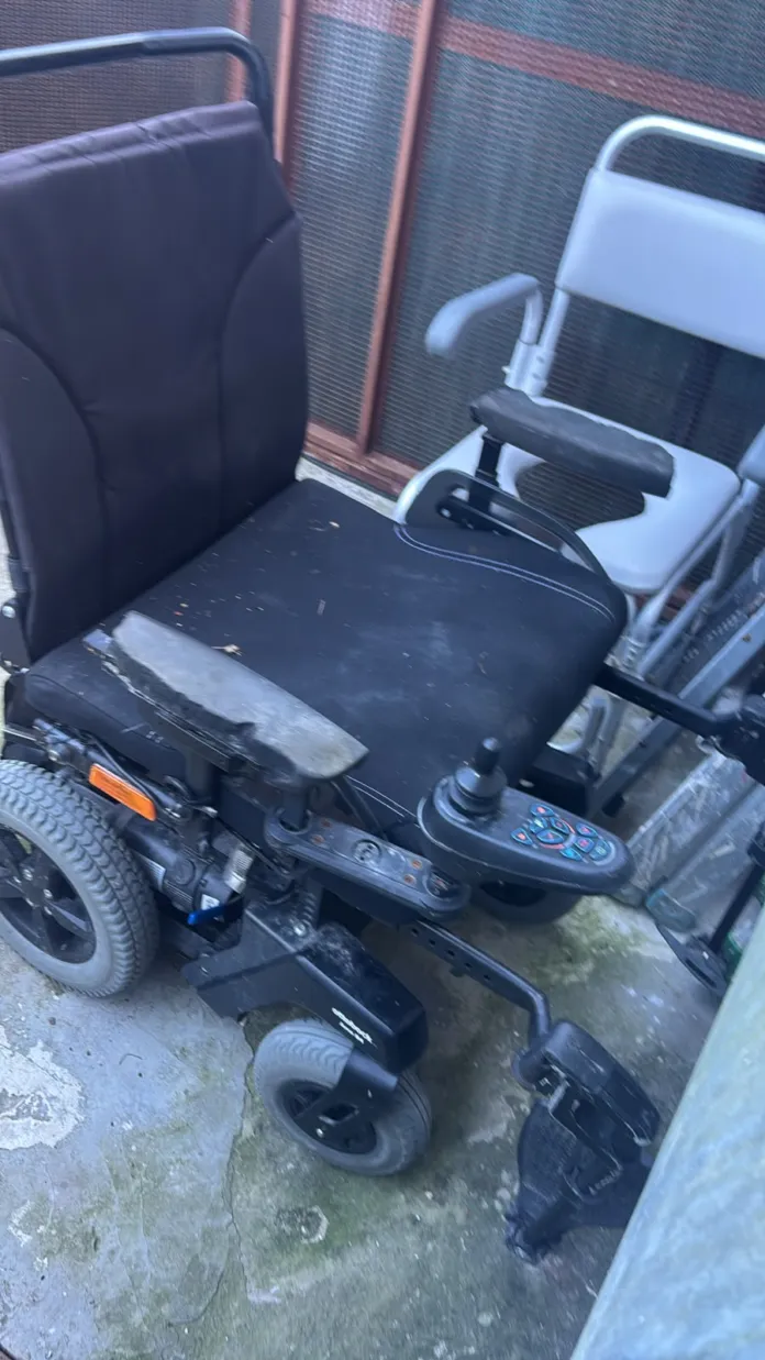 Sedia a rotelle elettrica nera con comandi sul bracciolo.