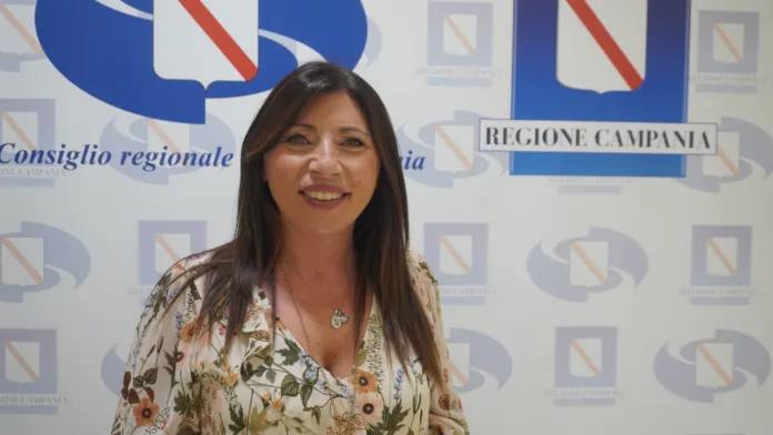 Una donna davanti a un fondale con la scritta «Regione Campania» e altri loghi istituzionali.