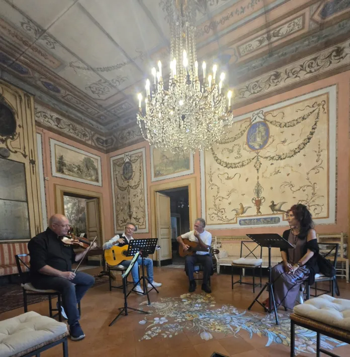 Quattro musicisti suonano strumenti in una sala con pareti e soffitto decorati.