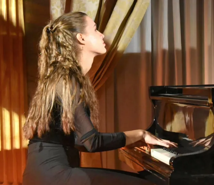 Una persona seduta al pianoforte, ripresa mentre suona.