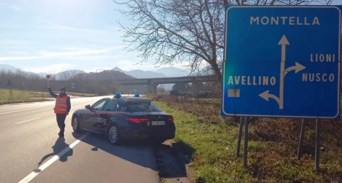 Un’auto dei Carabinieri è ferma sul margine della strada accanto a un cartello con l’indicazione Montella.