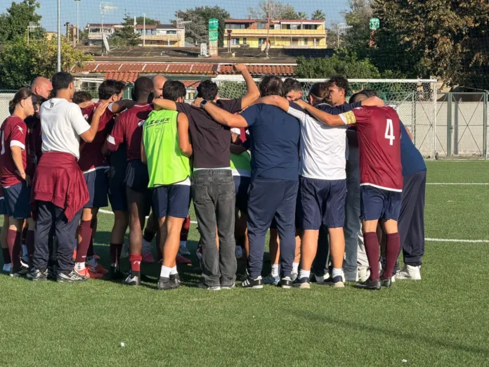Fotografia di una squadra di calcio che si riunisce in cerchio sul campo prima dell'inizio della partita, in un'immagine illustrativa.