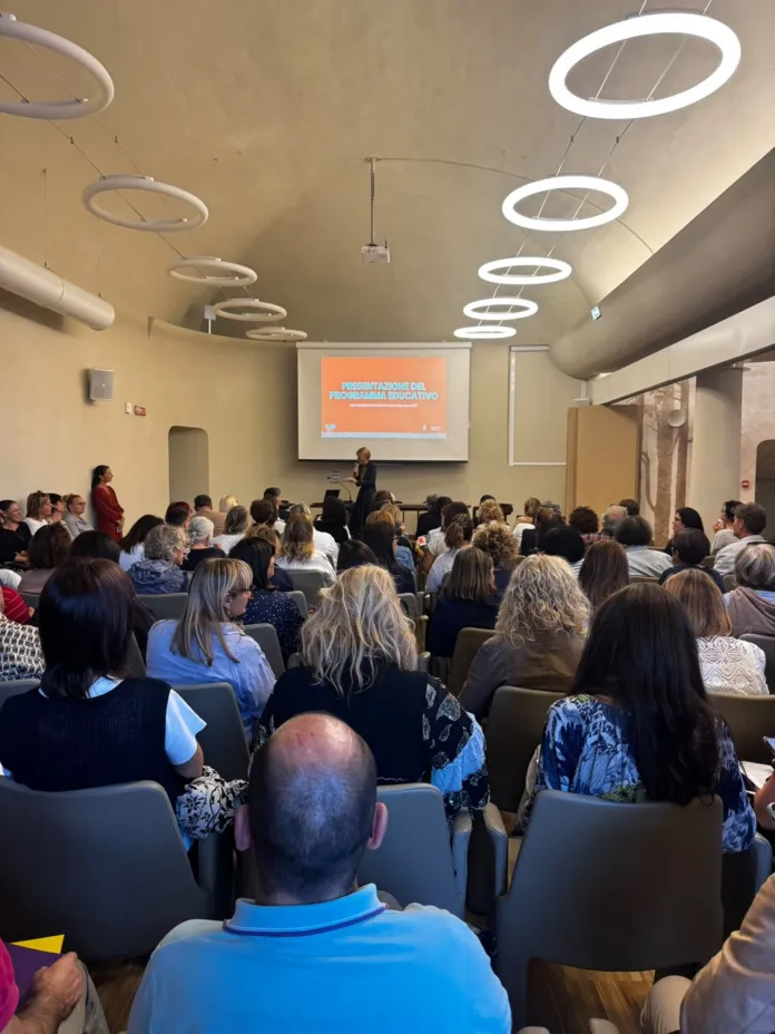Incontro pubblico con cittadini e docenti in una sala conferenze per presentare il programma educativo di Alba 2027.