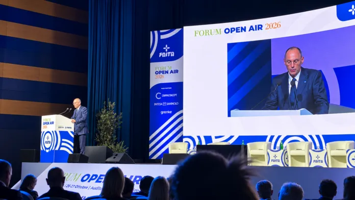 Un relatore è al leggio davanti a uno schermo con la scritta «Forum Open Air 2026»; in primo piano si vede il pubblico.