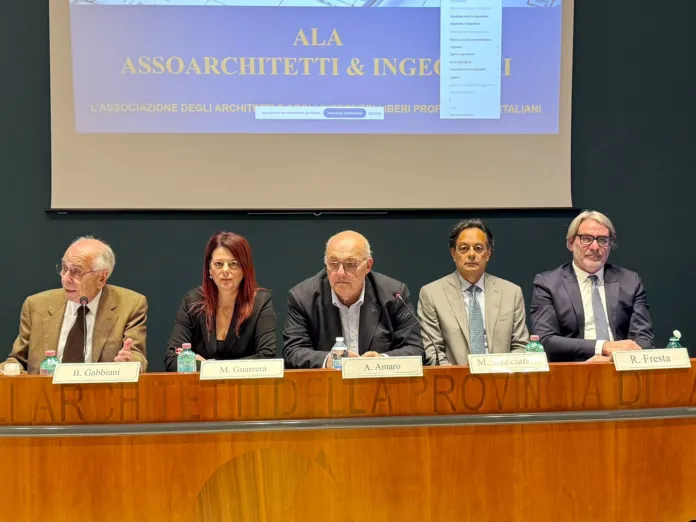 Cinque persone sono sedute dietro un tavolo, davanti a uno schermo con una presentazione.
