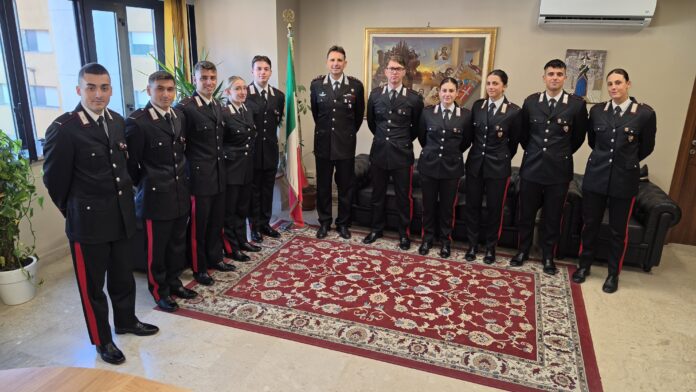 Gruppo di allievi marescialli in uniforme in una stanza con bandiera italiana.