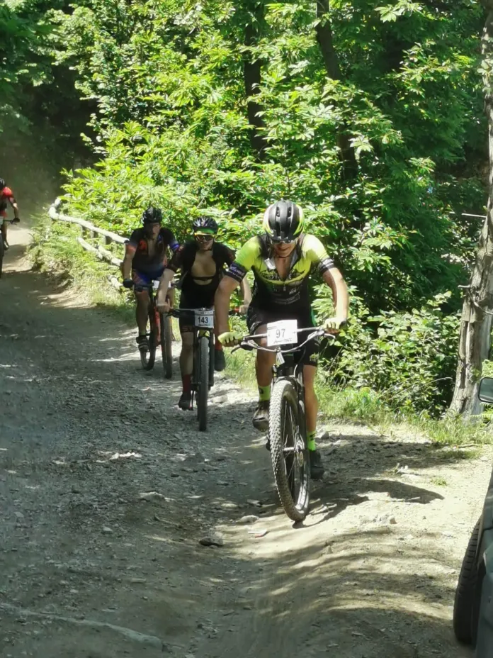 Partecipanti in mountain bike su sentiero sterrato in area verde durante gara di MTB