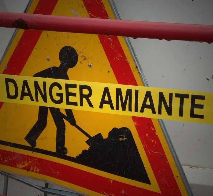 Cartello giallo di avvertimento con la scritta «Danger Amiante» e il simbolo di un lavoratore.