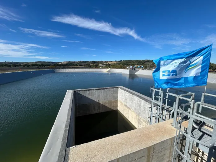 Un bacino d’acqua visto da una struttura in cemento, con una bandiera blu sul lato destro.