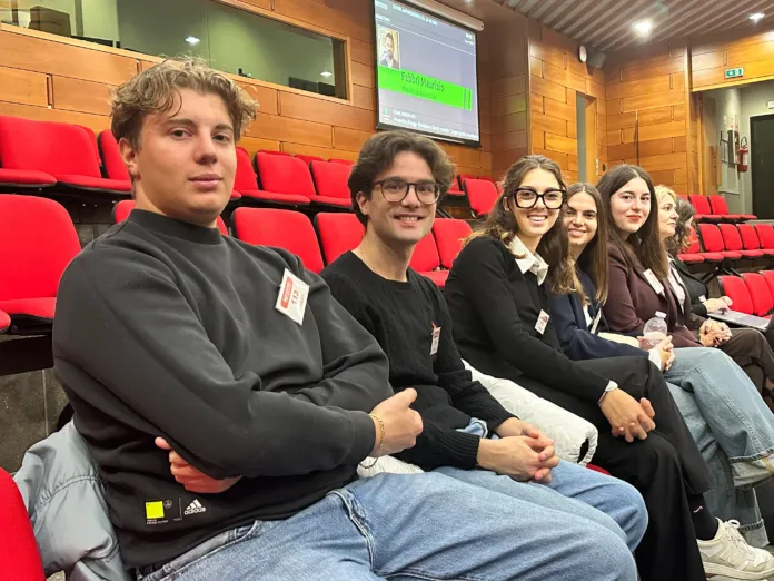 Fotografia di archivio di studenti universitari in una sala con sedili rossi, durante una visita all'Assemblea legislativa.