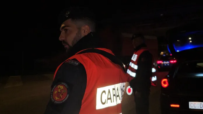 Controllo stradale notturno della polizia, agenti in alta visibilità e veicoli in controllo, immagine di archivio.